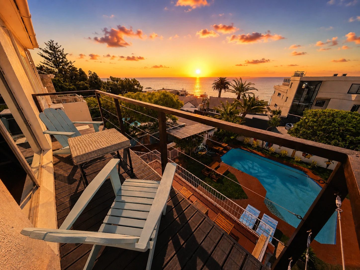 Sunset over the Atlantic from the Swordfish balcony, with blue chairs and the pool below